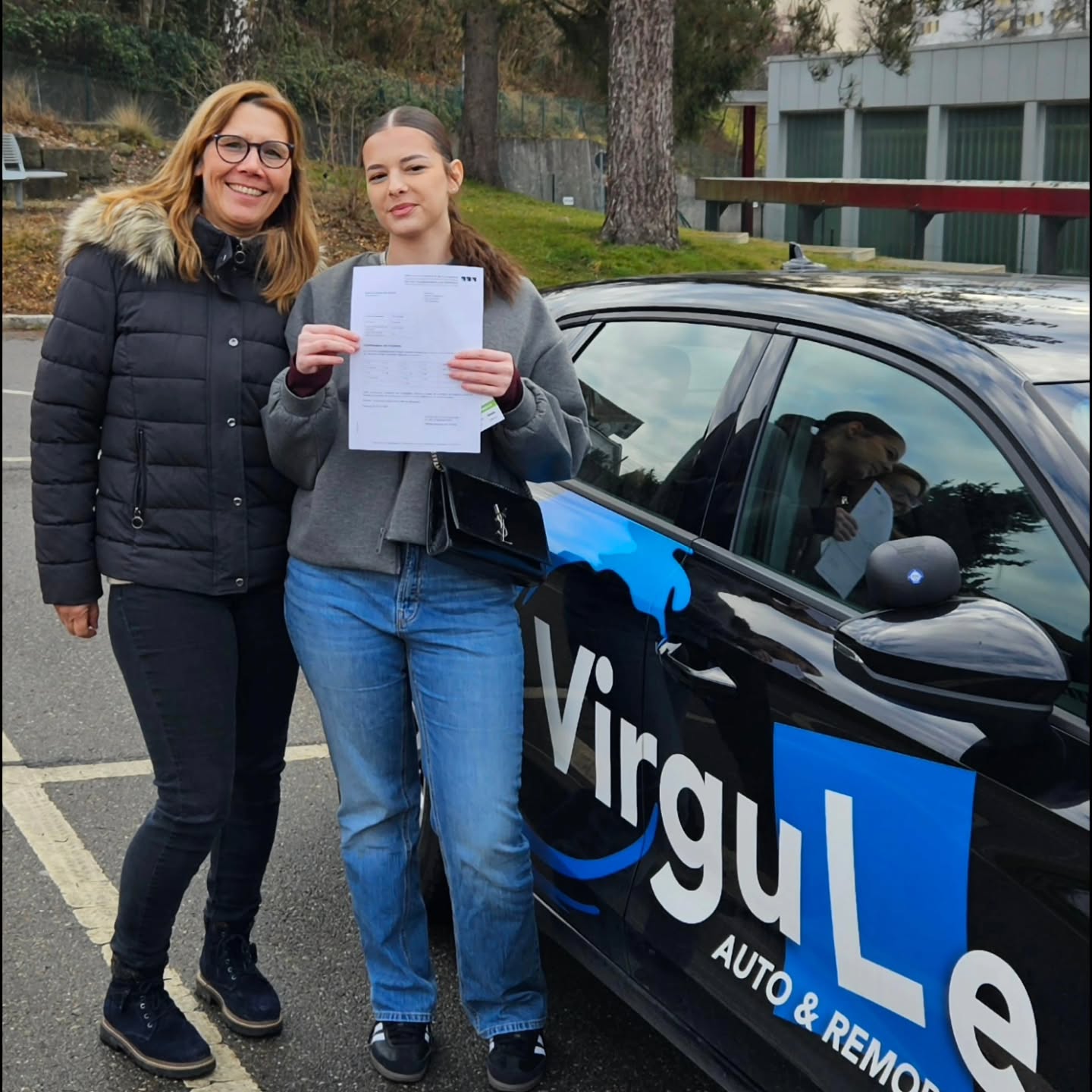 Véronique, monitrice de Virgule Auto-École, célébrant la réussite d'une élève à côté de la voiture-école