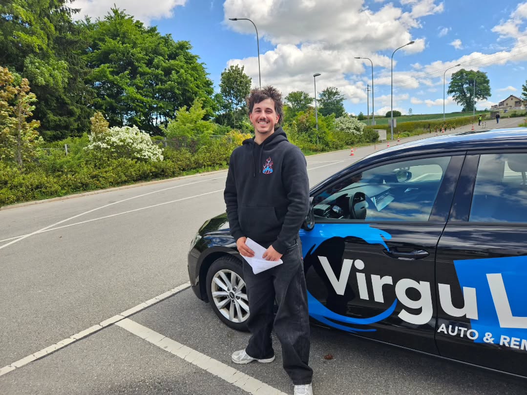 Dany, permis de conduire obtenu, devant la voiture-école Virgule